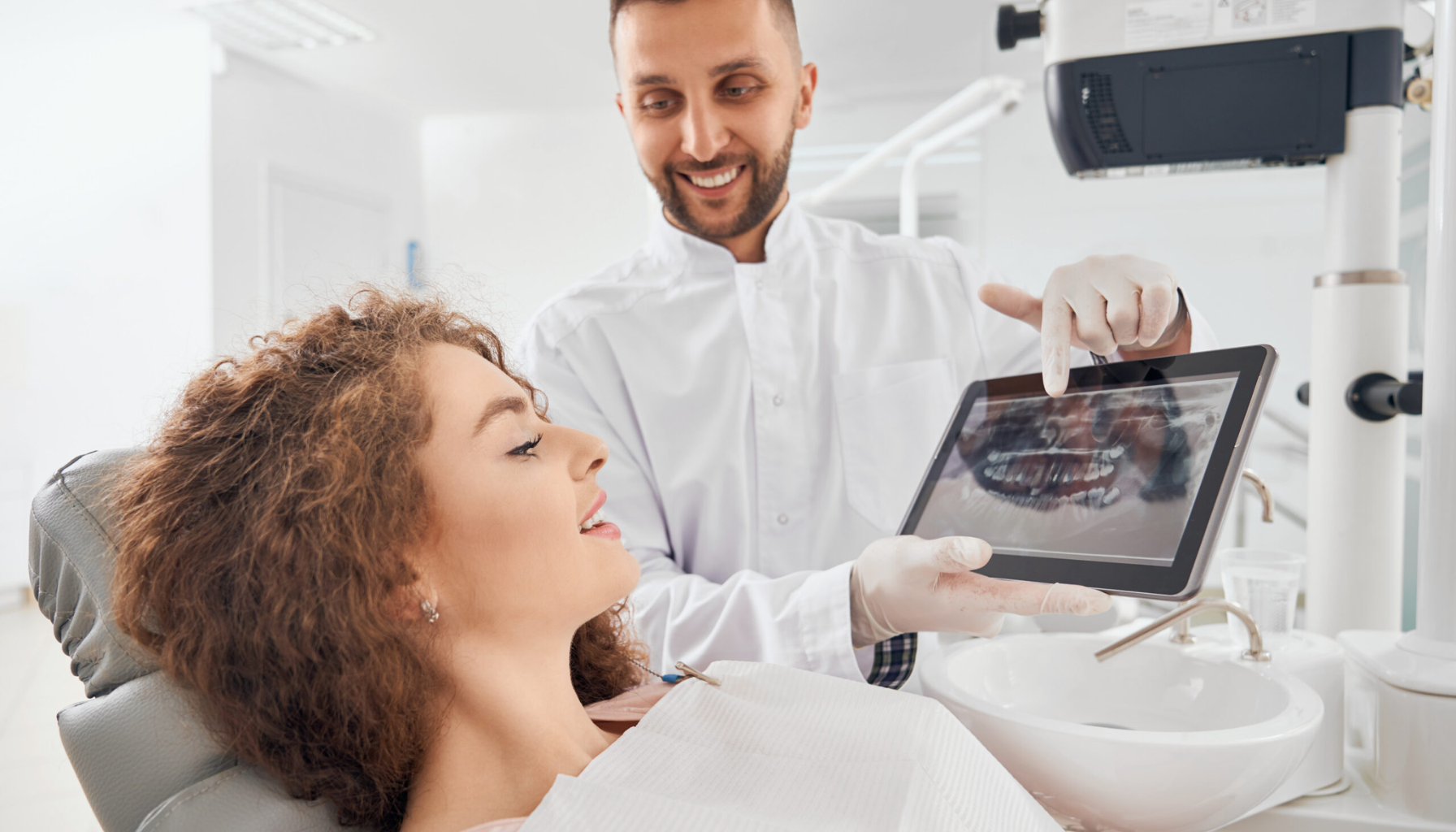 Achieve Your Perfect Smile with Digital Smile Design Technology 11 Dentist shows patient x-ray on tablet and explains treatment plan in modern dental clinic.