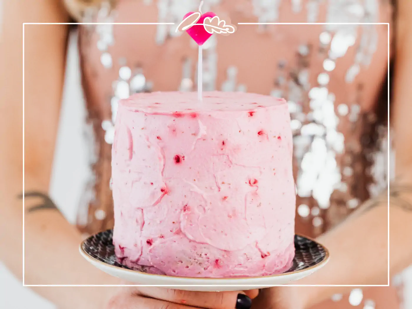 Close-up of a pink birthday cake with a single candle, fabulous flowers and gifts