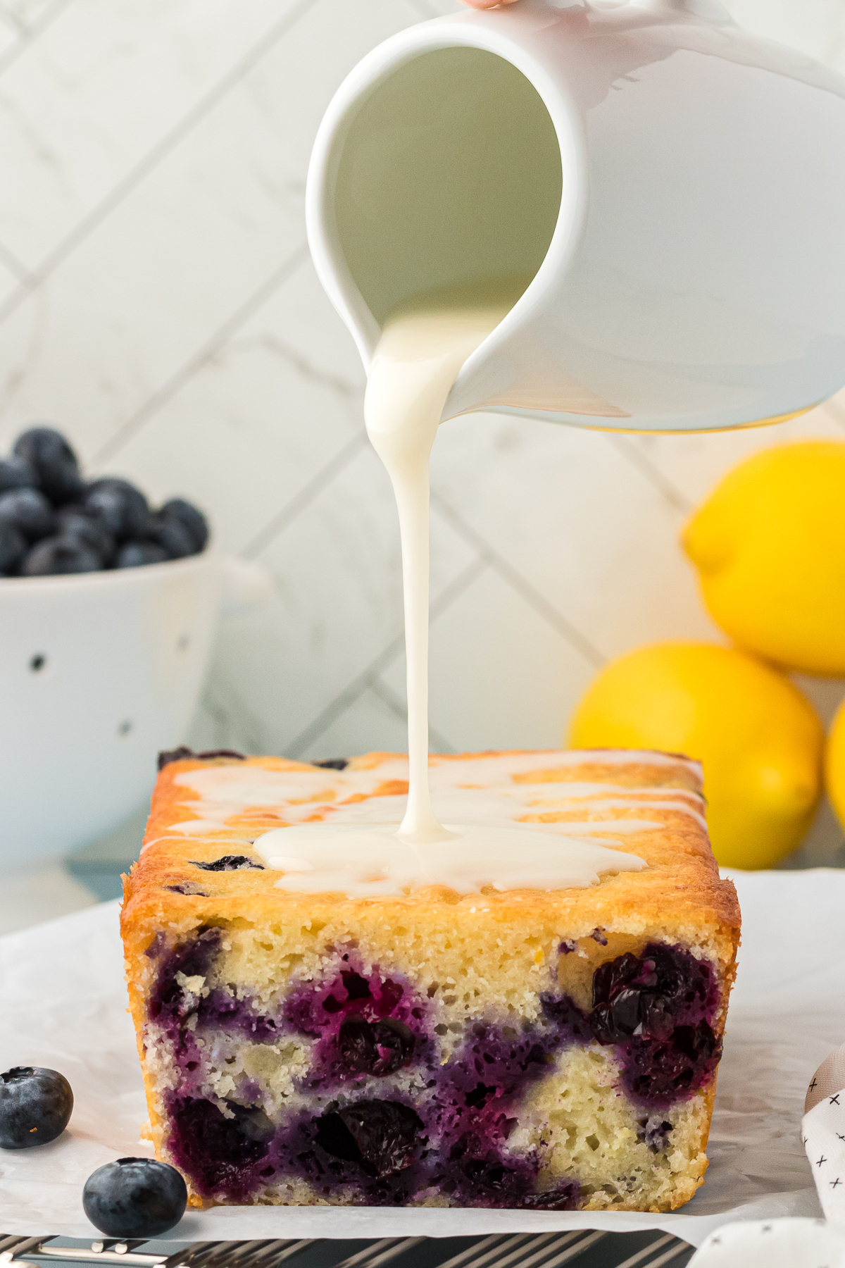 lemon glaze poured over blueberry lemon quick bread