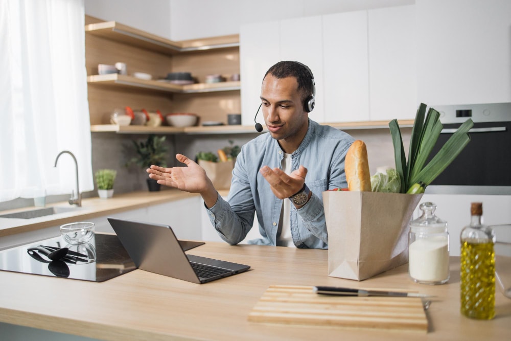 A business man working from home, video conferencing using a desktop and mobile apps.