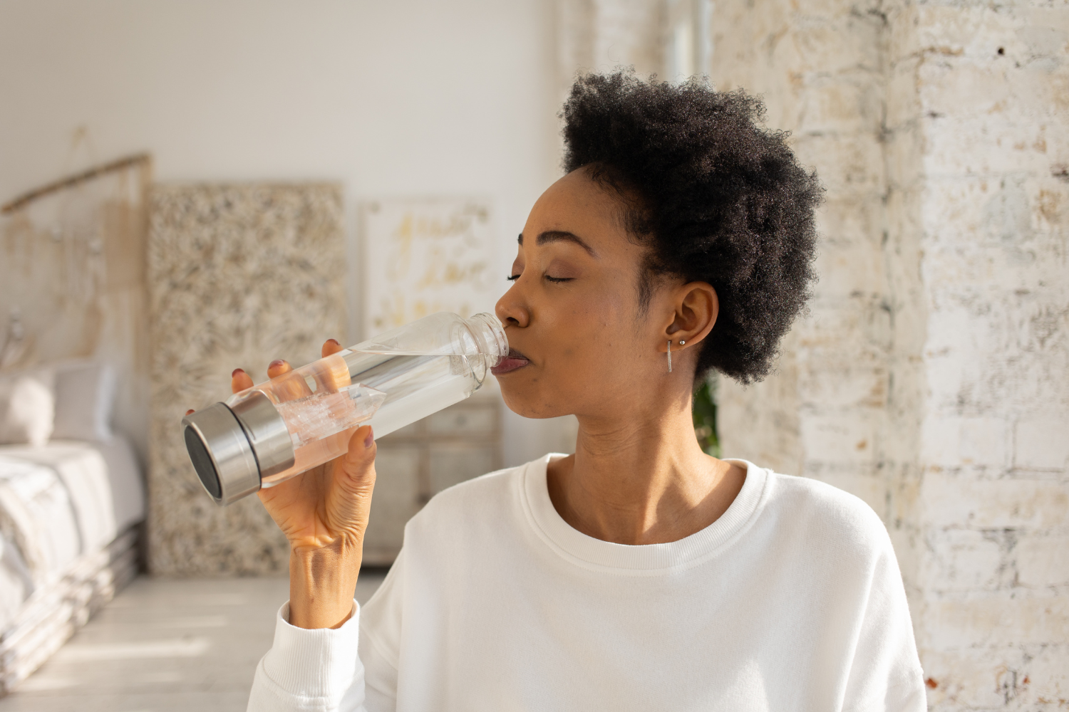 Woman drinking from a glass bottle.