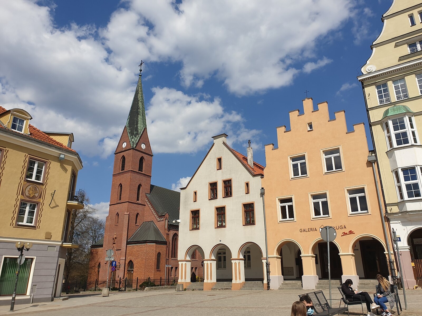 Zdjęcie Starego Miasta w Olsztynie z zabudową kamieniczek oraz kościołem oraz placem. Źródło: https://commons.wikimedia.org/wiki/File:Stare_Miasto_-_Olsztyn_-_church,_Stare_Miasto_2_%26_3.jpg