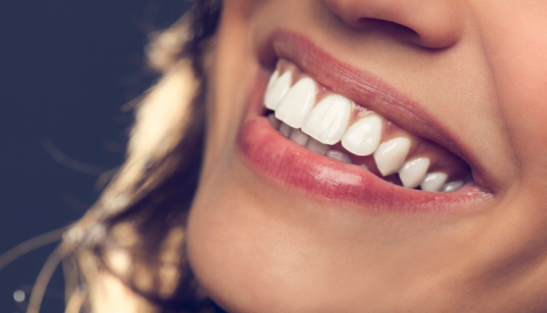 Nærbilde av en kvinne som smiler med sunne, hvite tenner og naturlige lepper.