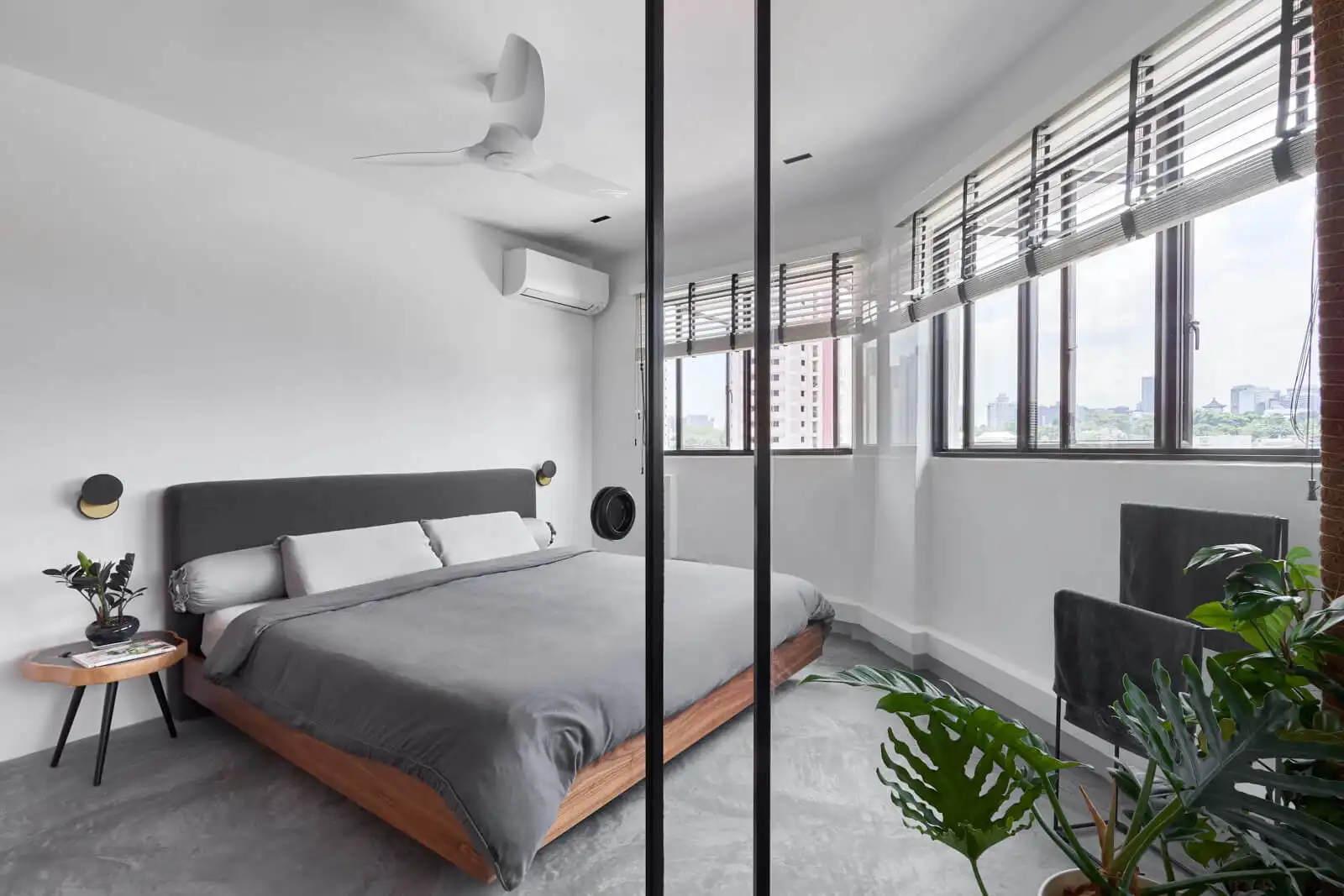 Minimalist room with large windows, platform bed and wall sconces, plants adding warmth