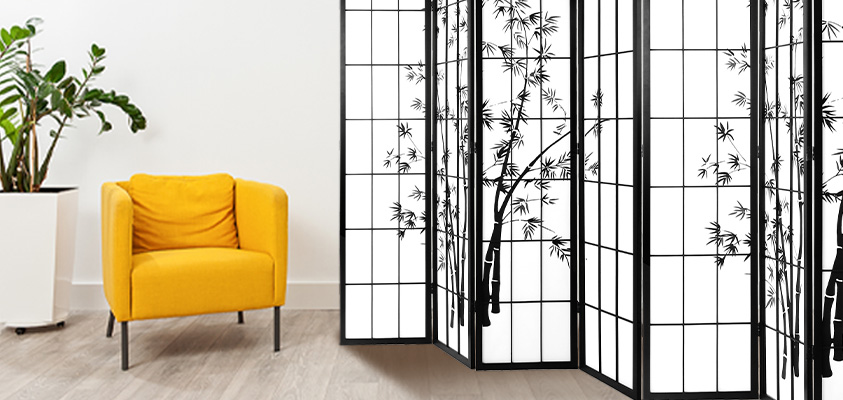 An Artiss printed black and white privacy screen, set next to a yellow armchair and tall pot plant.