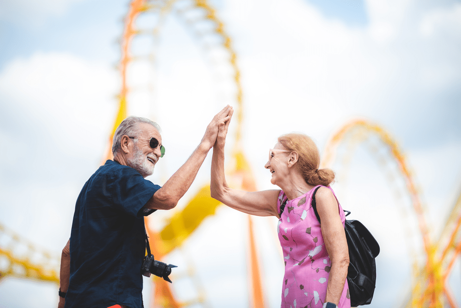 Couple high-fiving next to a roller coaster in New York City, celebrating their success in managing adult ADHD within their marriage, promoting happiness and resilience together.