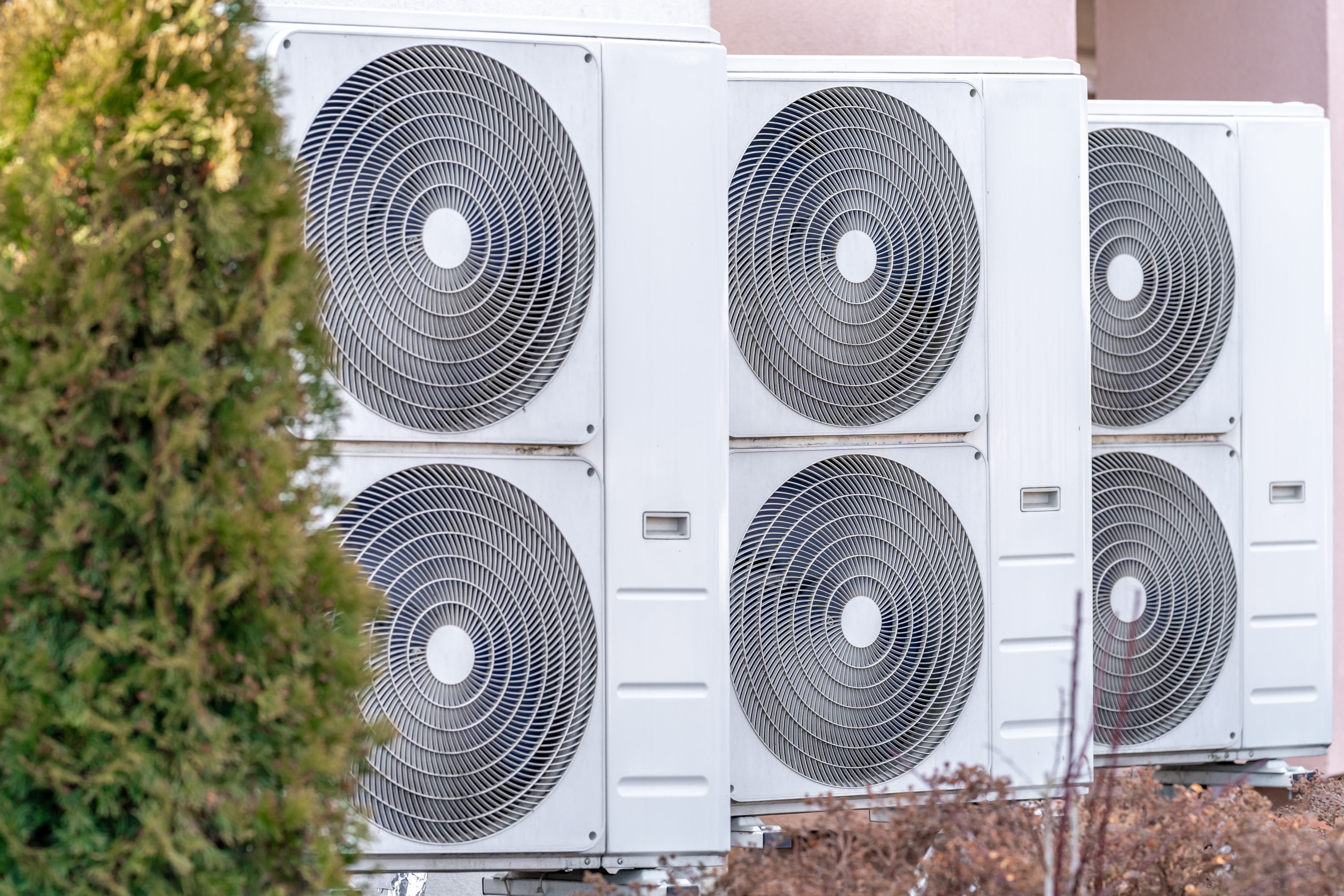 An outdoor heat pump unit surrounded by an acoustic enclosure for noise reduction.
