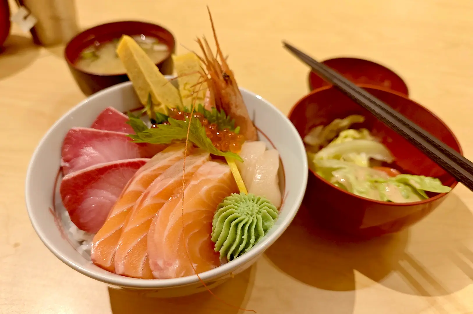 A vibrant bowl of premium chirashi don featuring fresh slices of raw salmon, tuna, shrimp, and salmon roe served on vinegared rice.