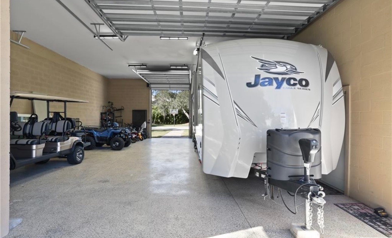 The image depicts a spacious residential property in Golden Gate Estates, Naples, featuring several RVs and boats neatly stored amidst natural landscaping. This private retreat showcases the perfect balance of outdoor space and storage options for recreational vehicles, highlighting the area's appeal for prospective properties consumers.