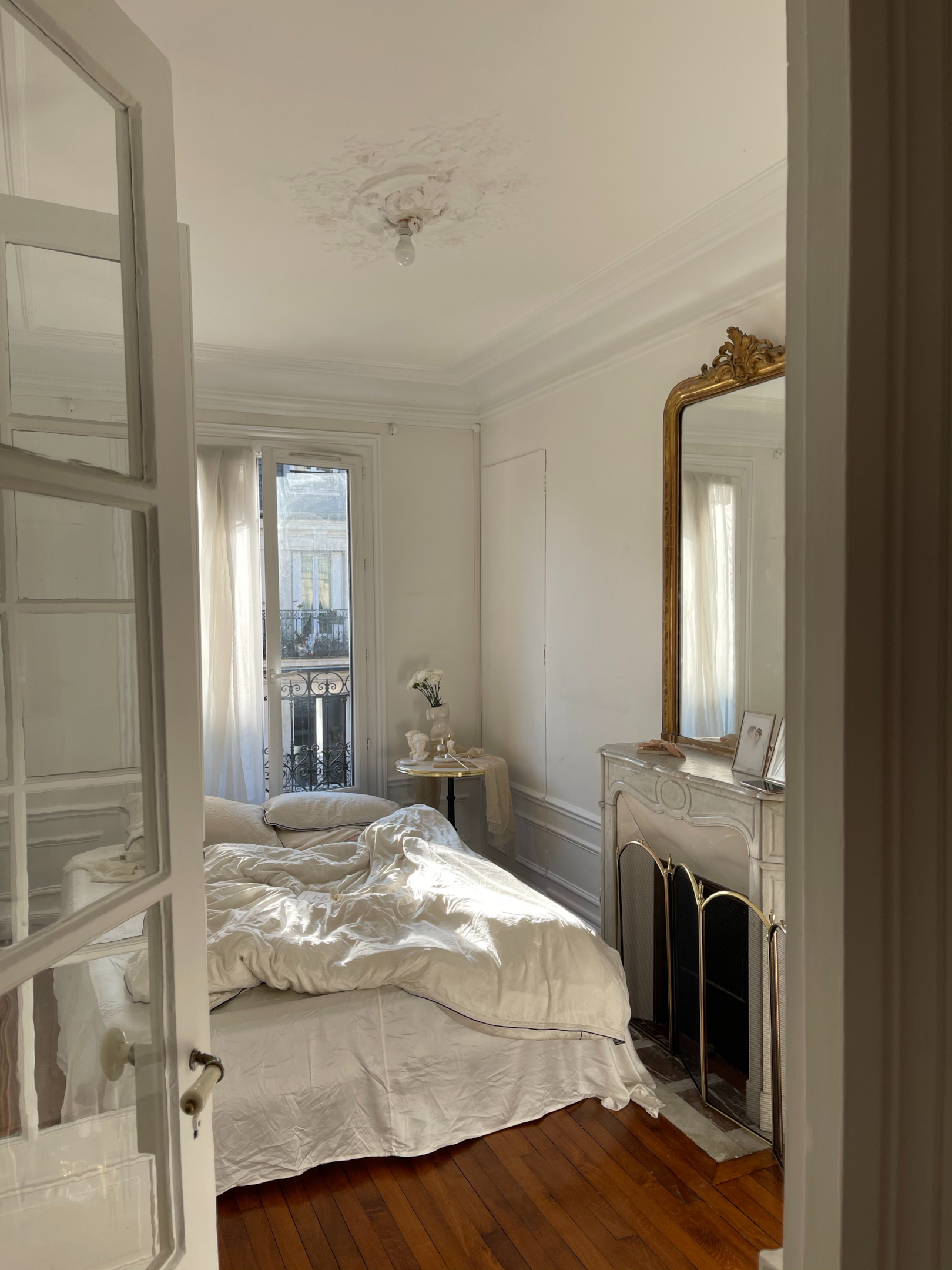 Interior master bedroom with French decor and antique mirror with natural light.