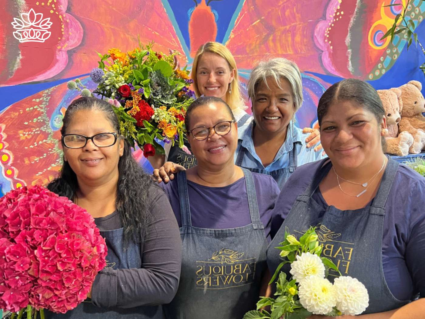 A group of friendly and experienced florists smiling warmly, holding vibrant bouquets, representing the dedicated team behind the scenes at Fabulous Flowers and Gifts.