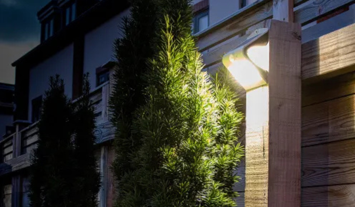 Solar powered flood light - wood fence mounted - in garden at night