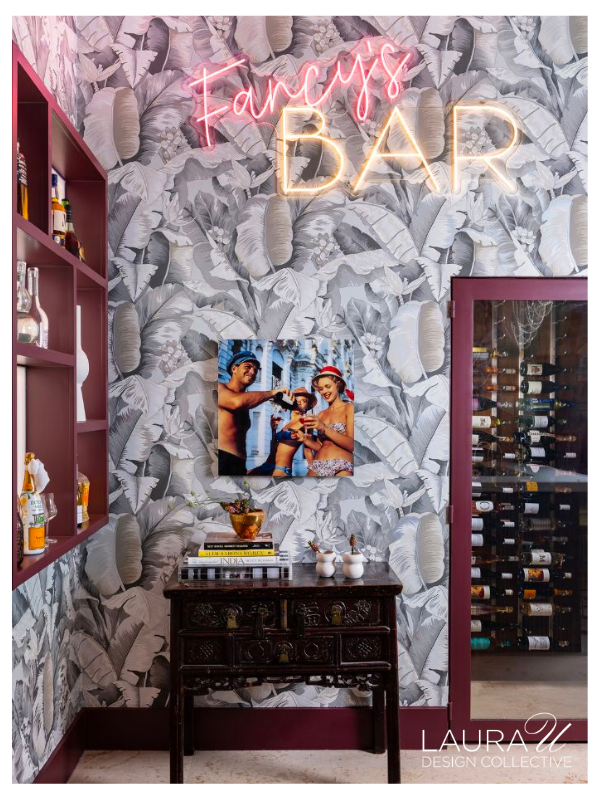 Tropical wallpaper, burgundy shelving, a neon Fancy’s Bar sign, and a glass-fronted wine cellar at Sandalwood.