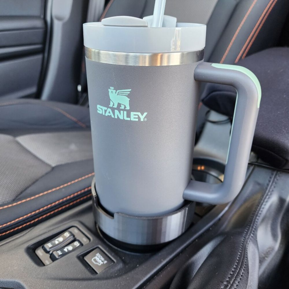 A car cup holder with a Stanley Tumbler in it