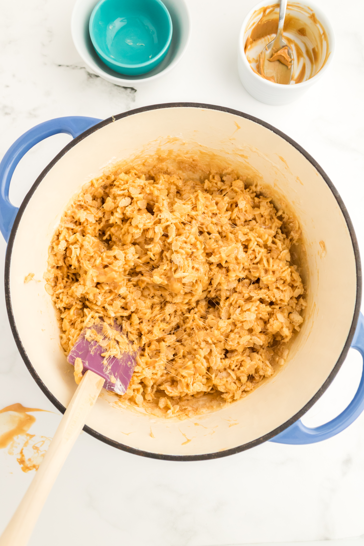 peanut butter rice krispie treat mixture in stockpot with spatula
