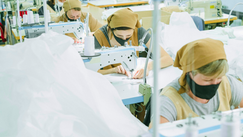 Several people are working on sewing machines, ensuring fabric quality standards