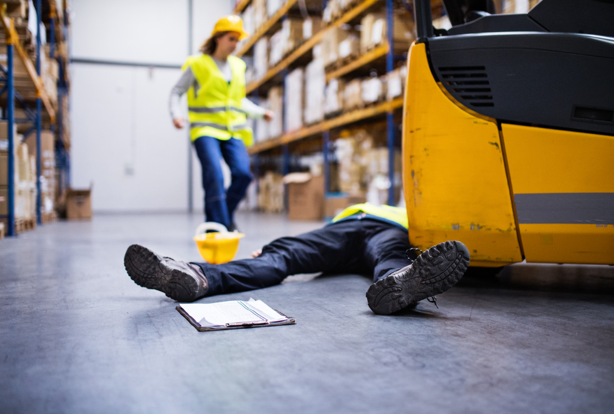 Collapsed warehouse worker next to forklift