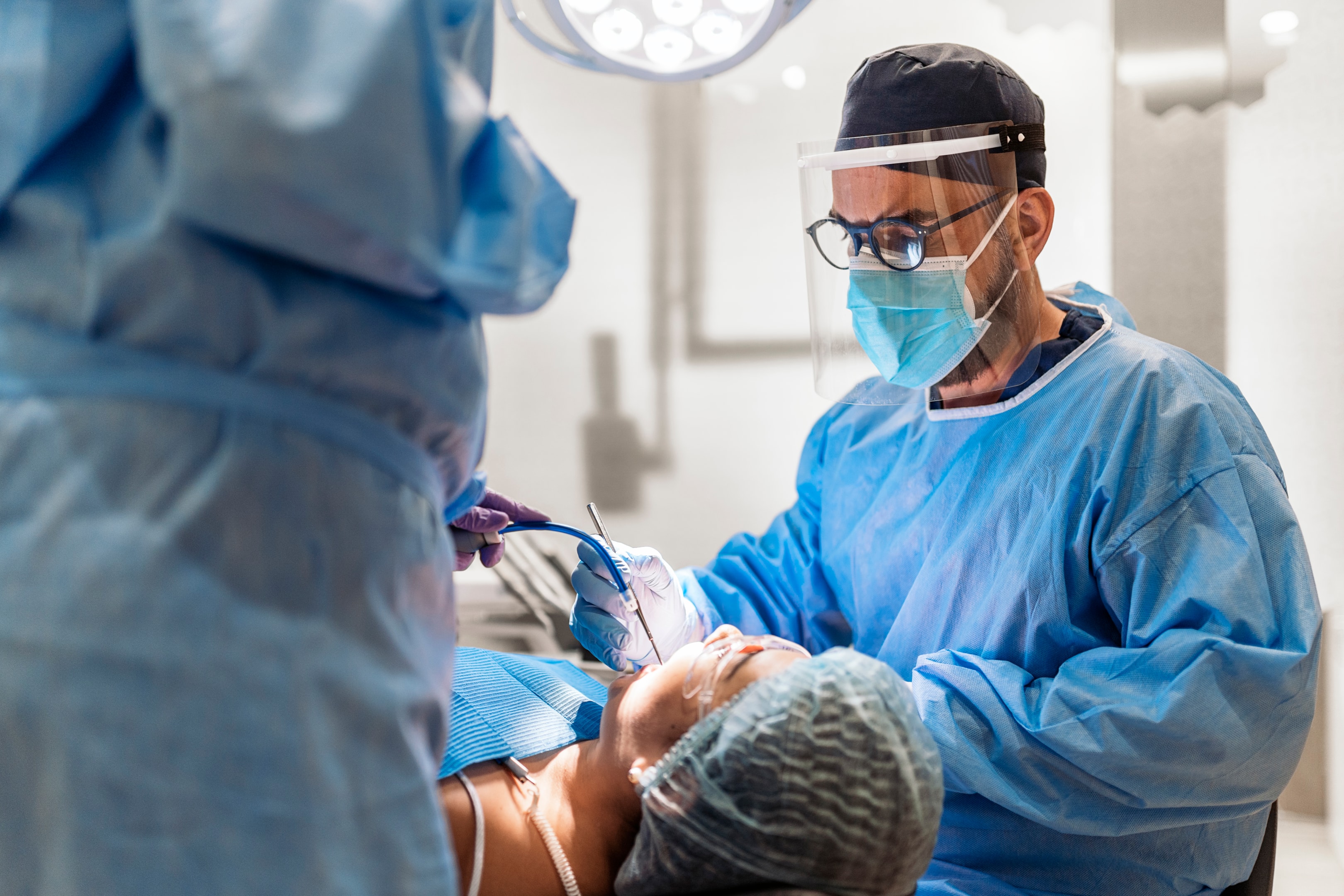 An image of an oral surgeon checking the adult teeth and preparing for dental extraction.