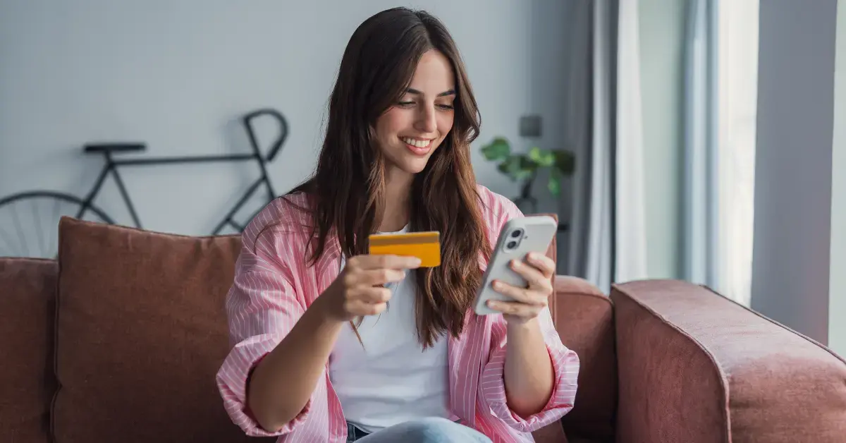 Woman holding a bank card after learning how to separate business and personal expenses.