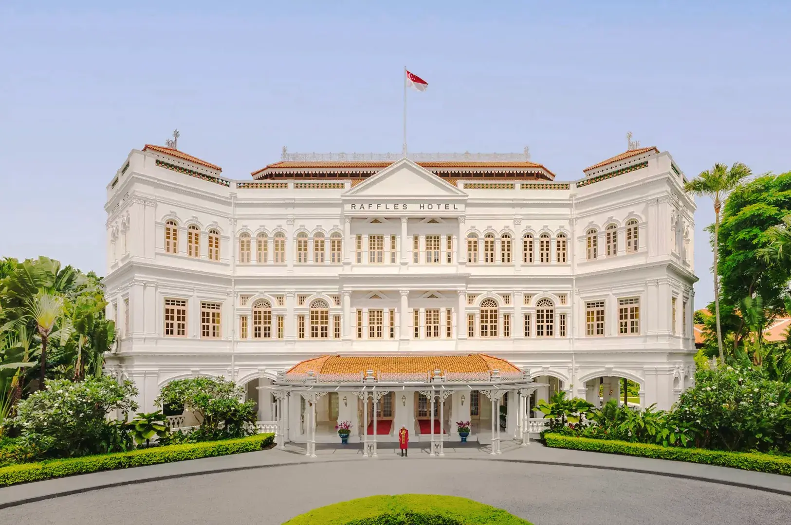 Historic Raffles Hotel Singapore colonial architecture with white façade, tropical gardens, and luxury heritage entrance.
