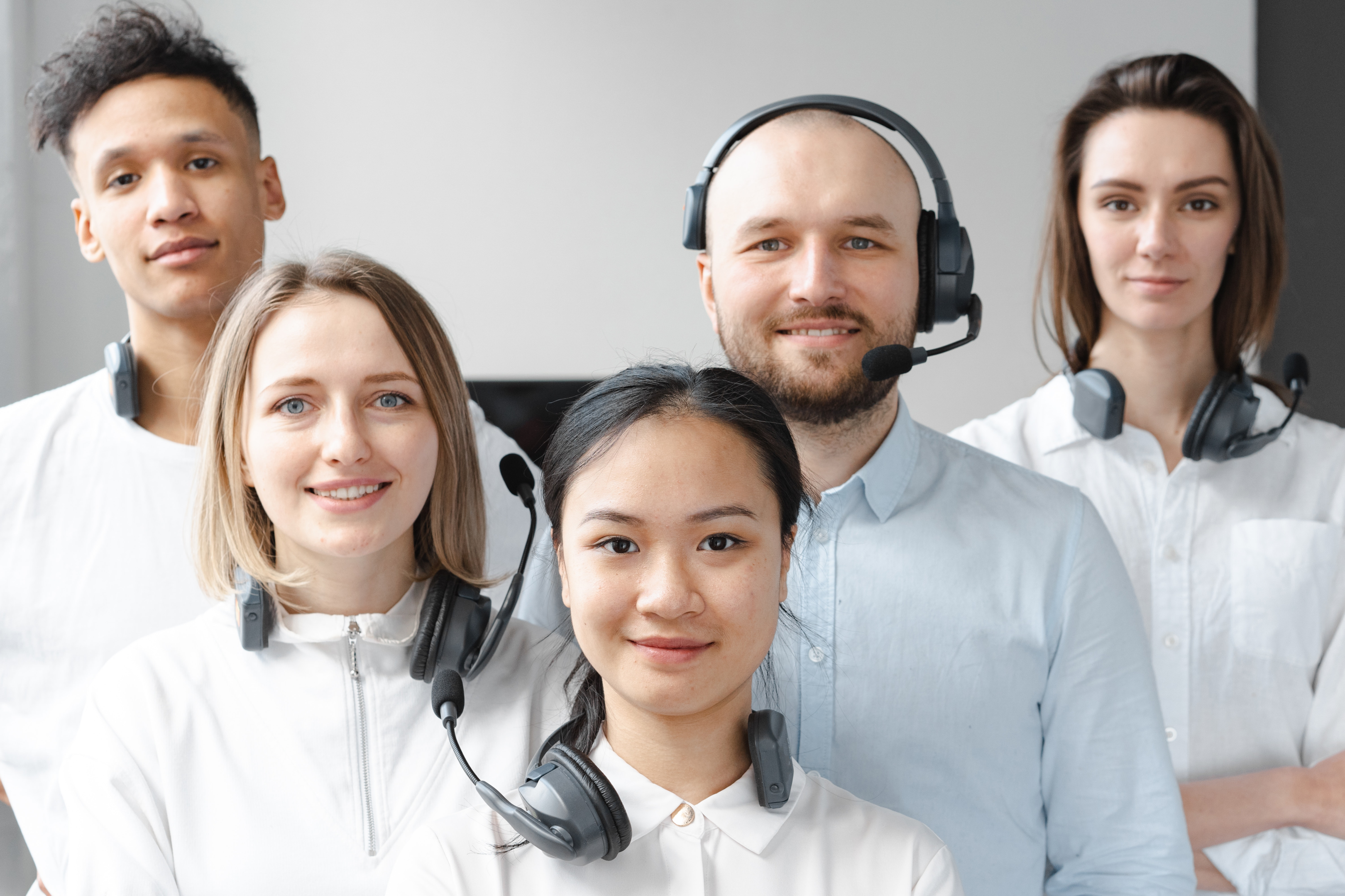 alt="Three women and two men wearing headsets and smiling" 