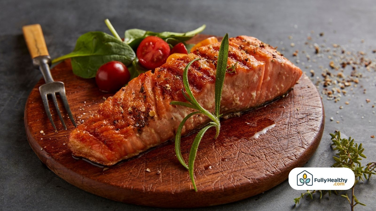 Pan-seared salmon filet on wooden board with tomatoes and herbs