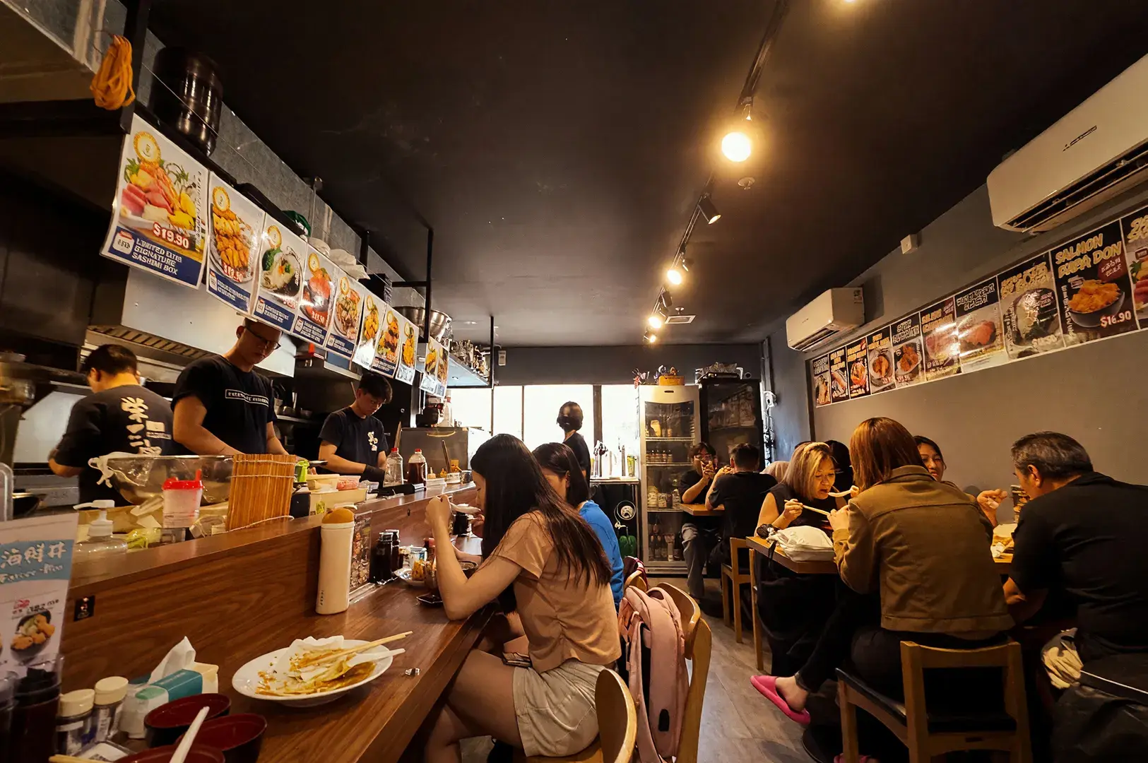 Cozy interior of Sakedoro Eizaburo at Fortune Centre, showing customers enjoying Japanese cuisine at the counter and tables.