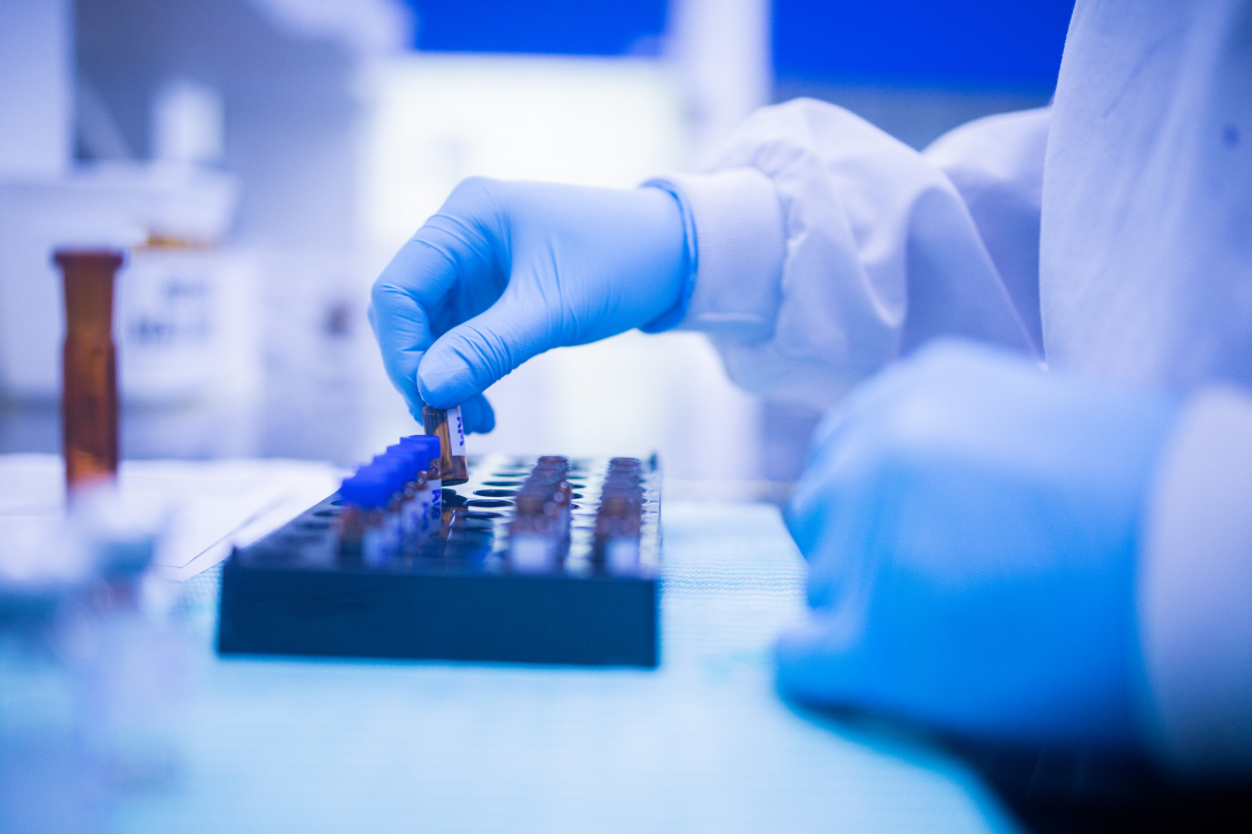 Gloved technician placing supplement vials for quality testing in a nutrition lab