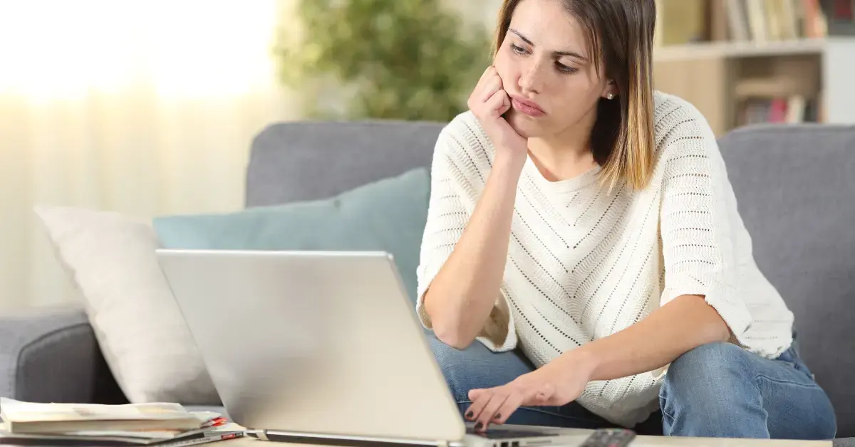 Woman reviewing monthly earnings on laptop showing irregular income challenges.