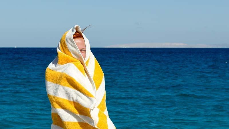 A young woman wrapped in a yellow beach towel