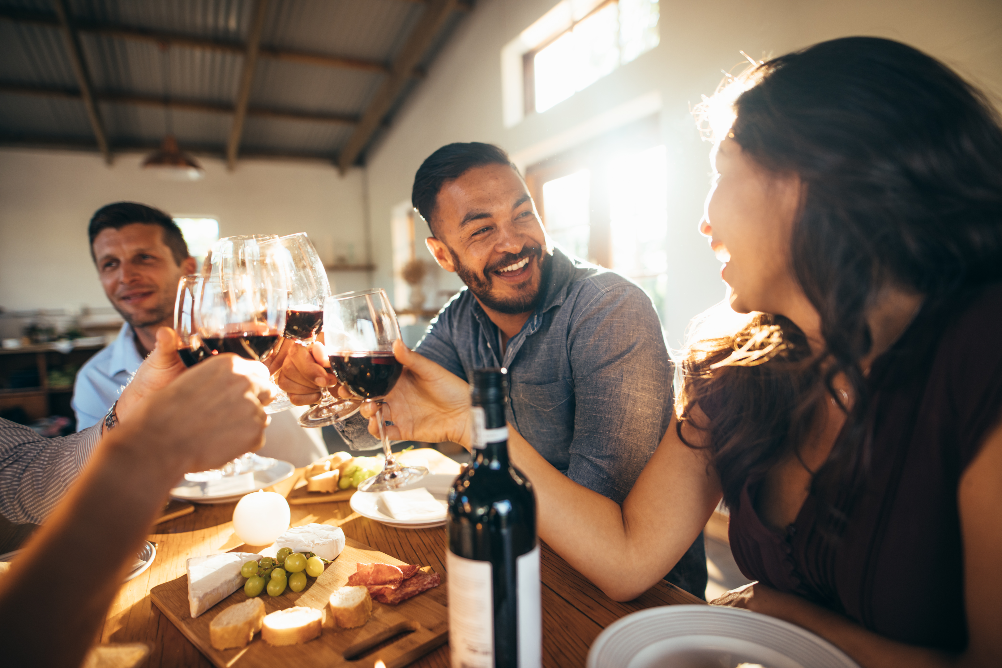 Man and woman laughing while toasting with wine.