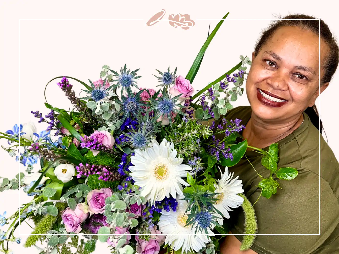 Smiling female florist with long curly hair, holding a colorful bouquet of flowers, standing in front of a pastel background - Fabulous Flowers and Gifts