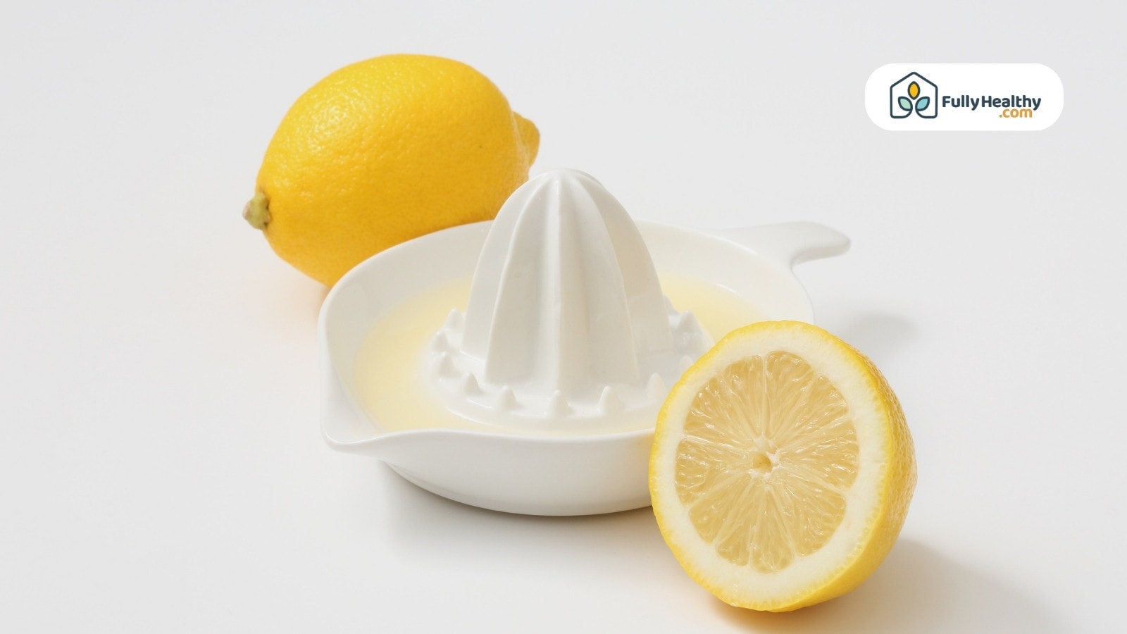 Lemon juicer with fresh juice and halved lemon on white surface