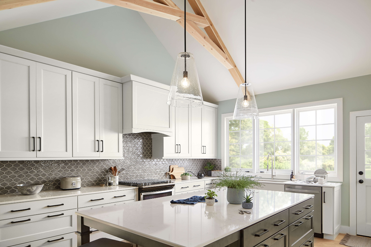 Glass pendant light fixtures over a white kitchen island, adding warm illumination and airiness to a bright modern kitchen.