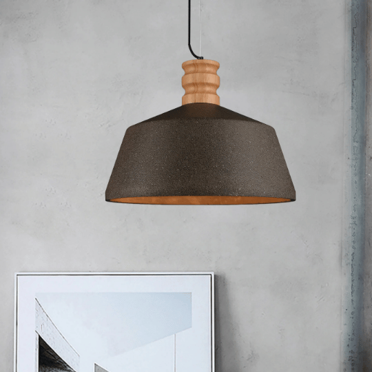Modern pendant light with a matte black shade and wooden top detail, hanging against a concrete wall above a framed minimalist artwork, creating a stylish contemporary look.