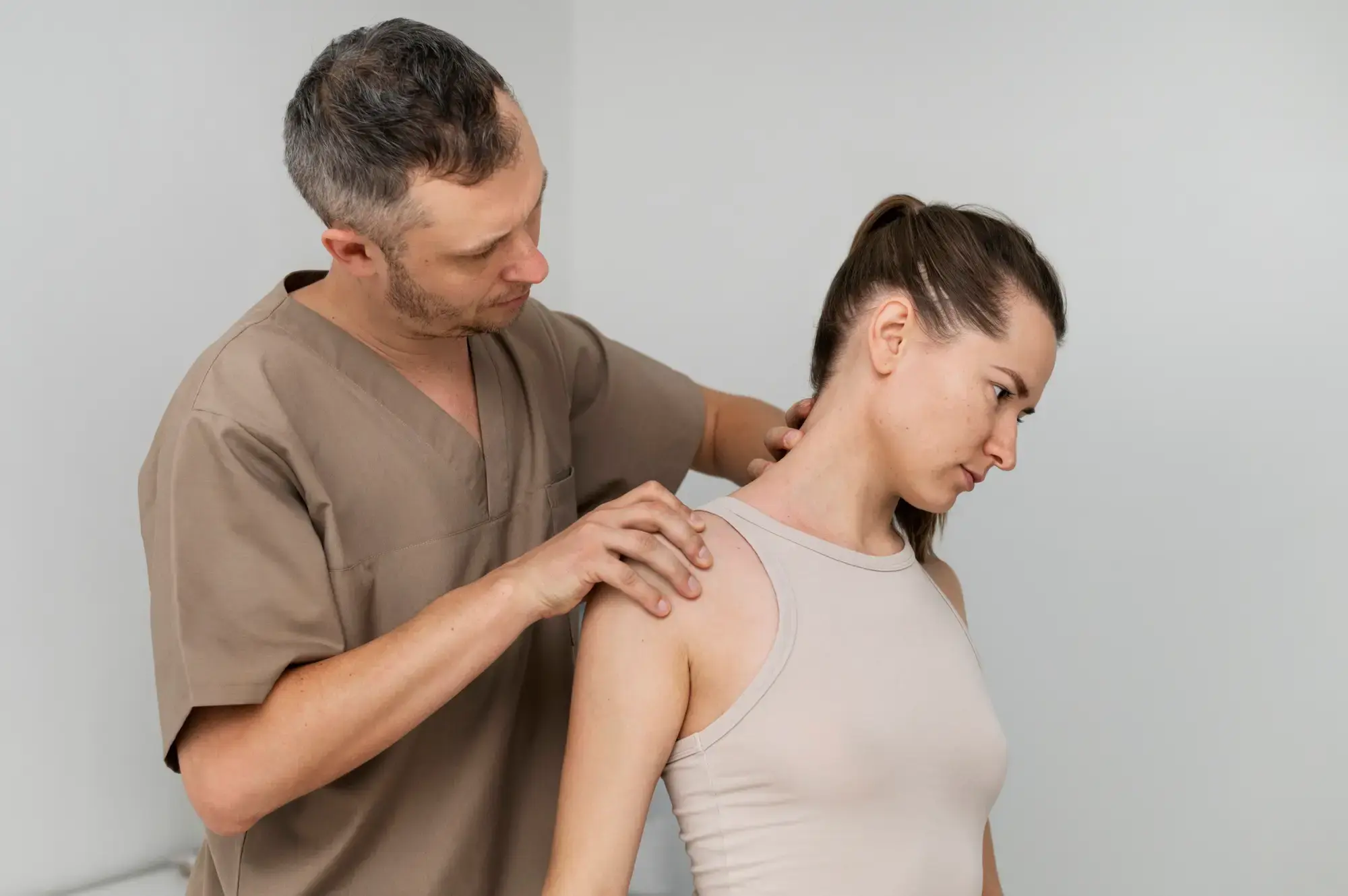Shoulder specialist for pain evaluating a woman’s neck and shoulder in a clinic