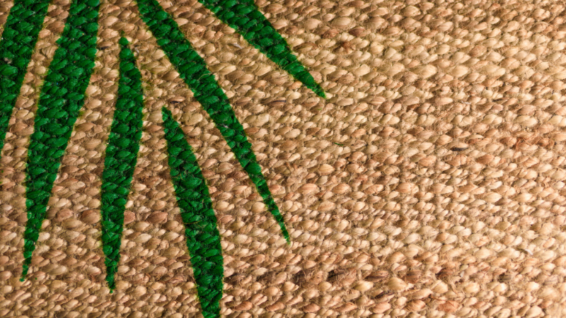 A close up of a green palm leaf on a jute bag