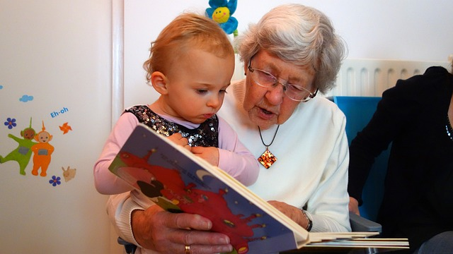 An image of a grandmother reading to her granddaughter sitting on her lap.
