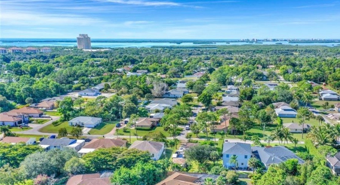 An aerial view of the desirable Meadowbrook community in Estero, Florida, showcases two scenic lakes surrounded by bright and spacious single-family homes. This picturesque setting highlights the community's charm, with well-maintained sidewalks and a tranquil atmosphere perfect for residents.