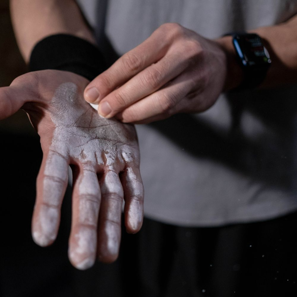 A person applying gym chalk to their hands before a workout