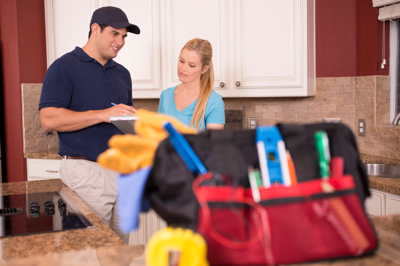 Installateur erklärt Kundin in der Küche Service-Details neben Werkzeugtasche.