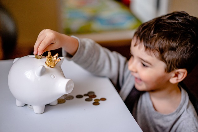 Free smiling kid putting a coin in a piggybank Stock Photo