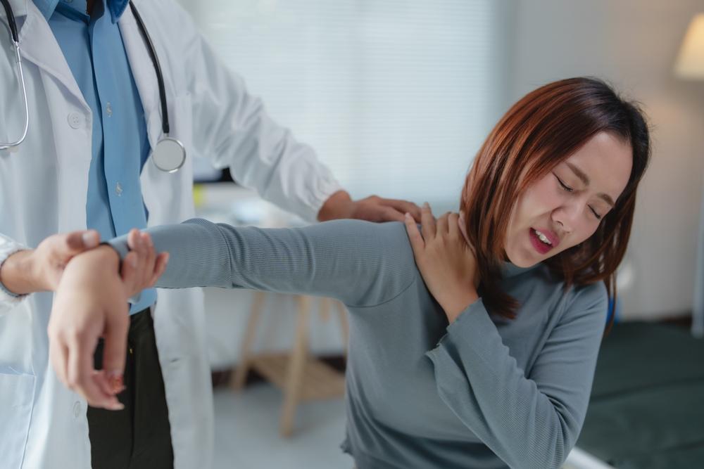 Woman experiencing shoulder pain during a clinical shoulder exam