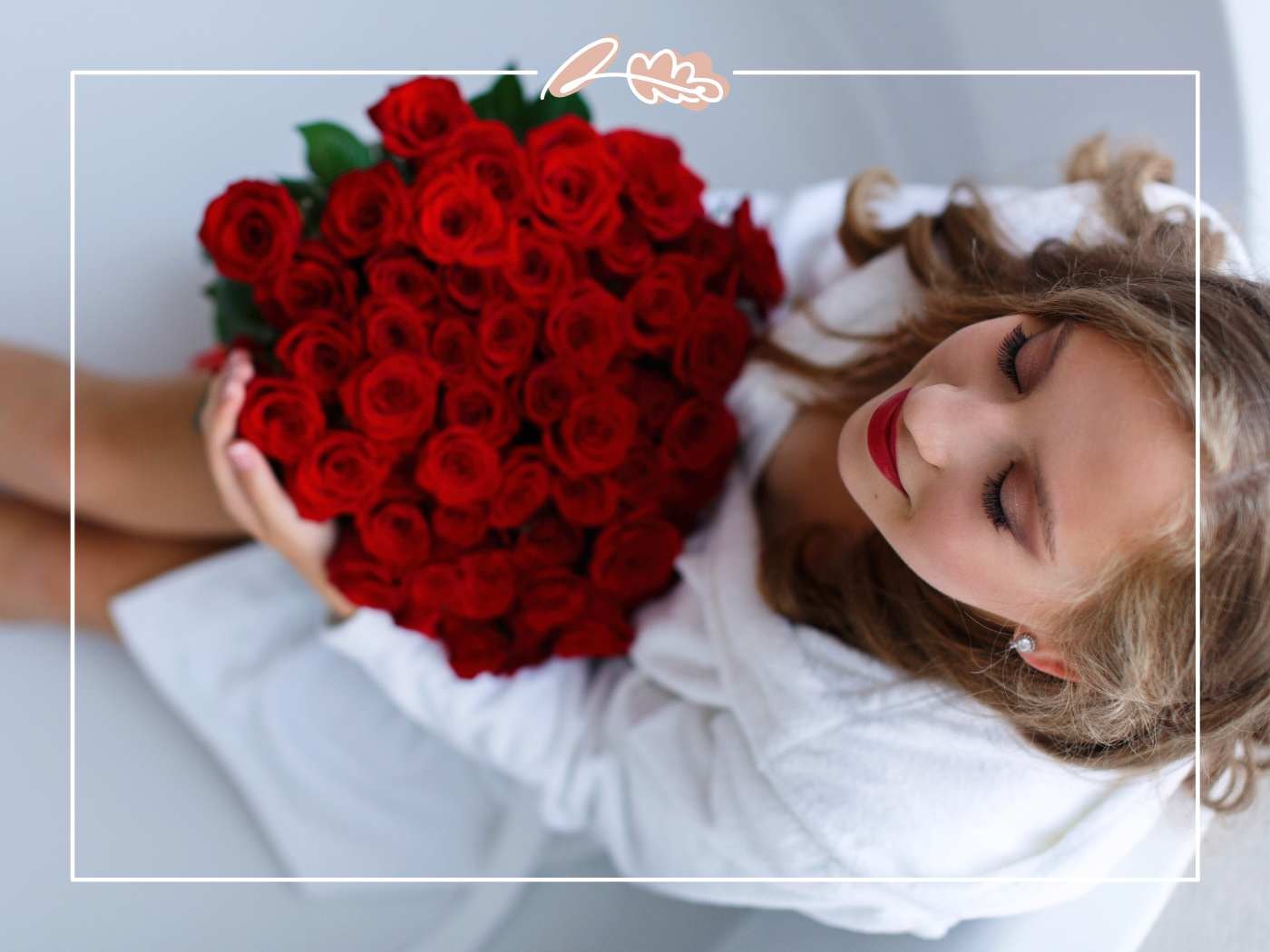 Woman in white holds a heart-shaped bouquet of red roses, eyes closed, with Fabulous Flowers border.