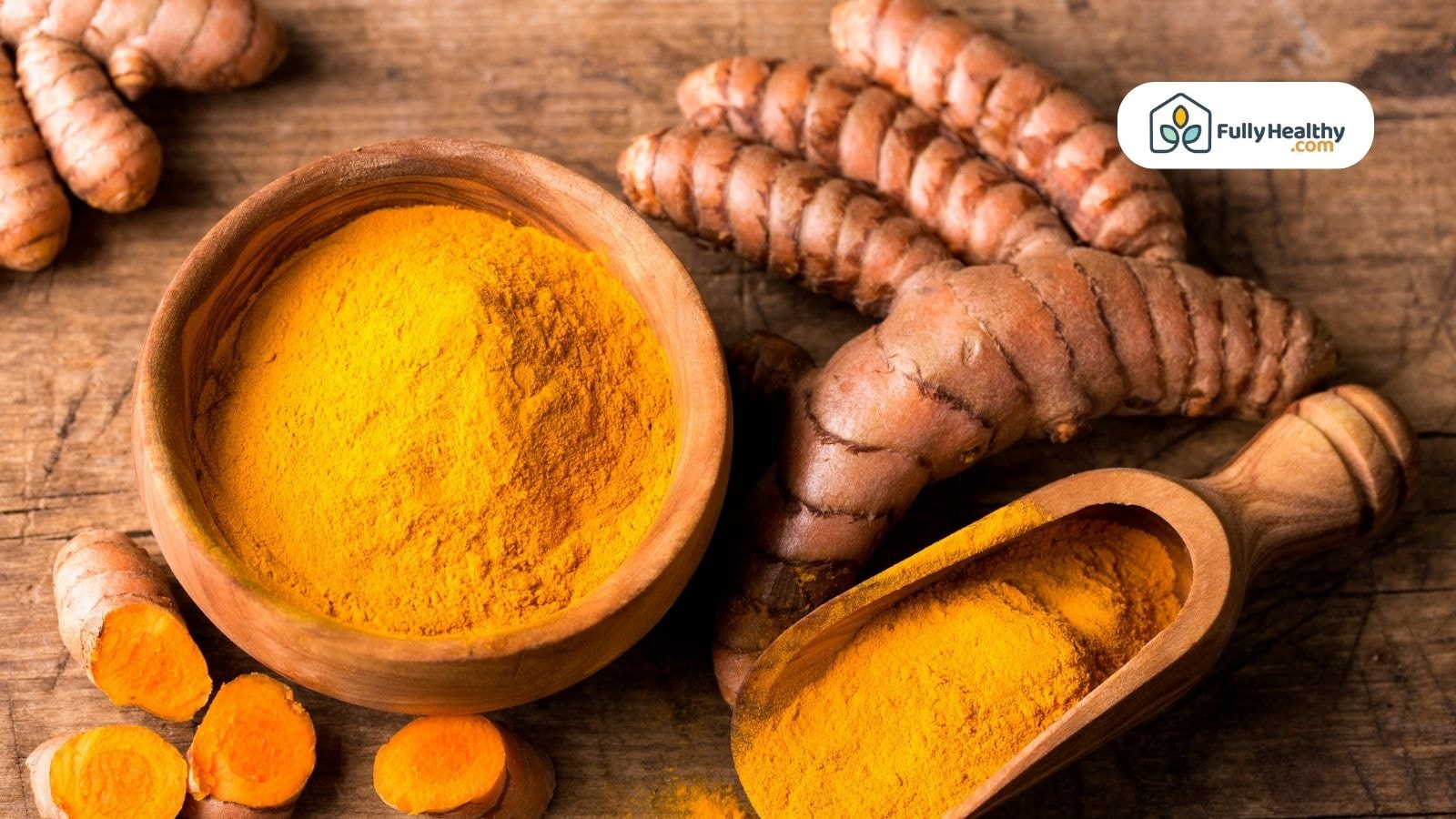 Bowl of turmeric powder and fresh turmeric roots on wooden table