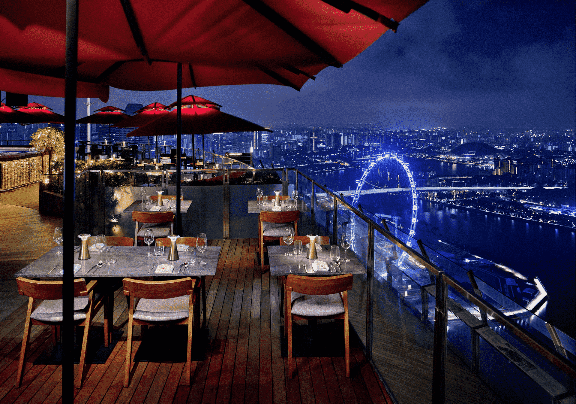 Nighttime rooftop dining with a view in Singapore featuring alfresco balconies, candlelit tables, and signature cocktails under red umbrellas, overlooking the city skyline and panoramic views of Marina Bay. This romantic restaurant offers stunning views of Marina Bay Sands, Marina Bay Financial Centre, and the illuminated city lights of Downtown Singapore. Among the best rooftop restaurants and rooftop bars in the Marina Bay area, near Sentosa Island, Mount Faber Peak, Ocean Financial Centre, Customs House, Collyer Quay, Civic District, Raffles Place, and OUE Bayfront. Ideal for happy hour, special dinner, weekday lunch, or private dining rooms, with a menu of contemporary Asian cuisine, modern Asian cuisine, European classics, small plates, freshest seafood including Maine lobster, and dishes curated by executive chef Sam Chin and executive chef Oliver Hyde. A must-visit destination for rooftop dining and dining with a view Singapore, featuring an impressive selection of food and drinks in a luxurious dining room setting.