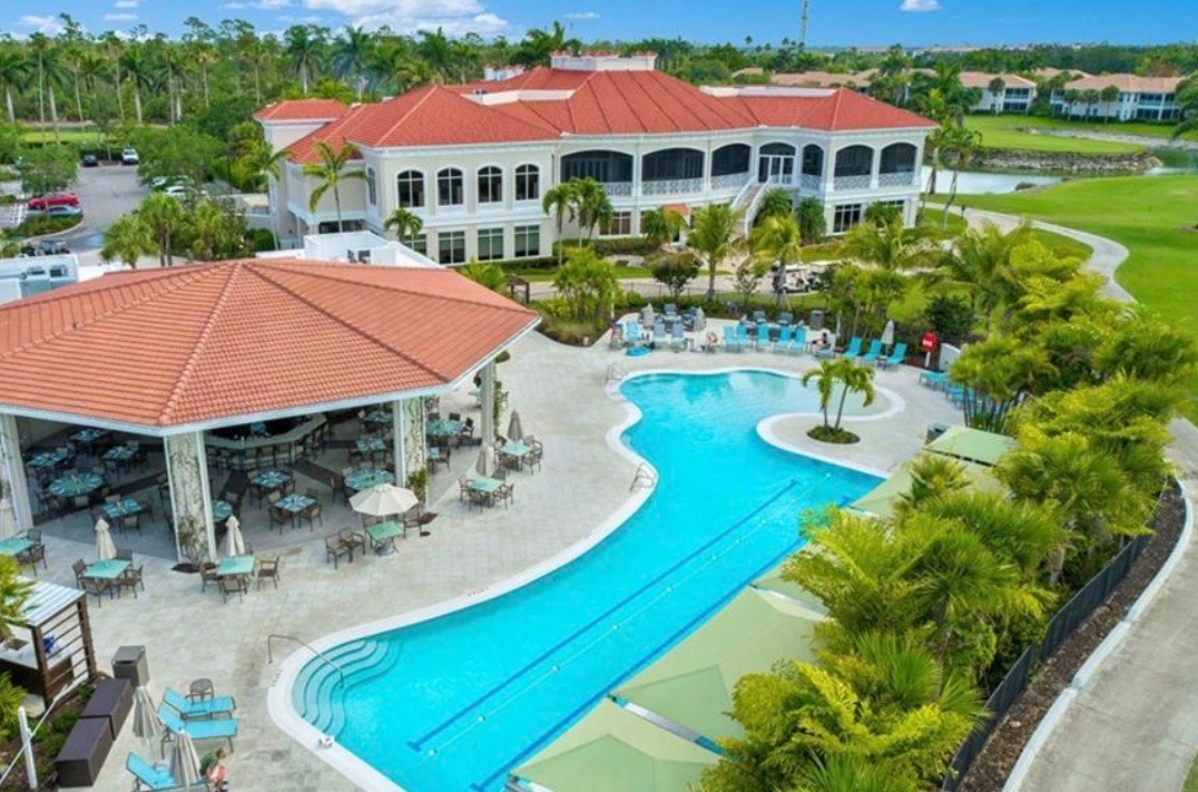 An aerial view of Naples Lakes Country Club showcases the beautifully designed Arnold Palmer signature golf course, surrounded by luxury homes and serene lakes, highlighting the community's resort-style amenities and scenic landscapes. The image captures the essence of modern living in a bundled golf community, perfect for those looking to enjoy a bundled golf membership and breathtaking views.