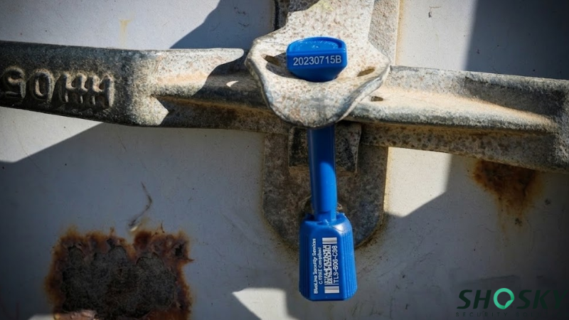 Blue high-security bolt seal locked on a weathered metal container latch