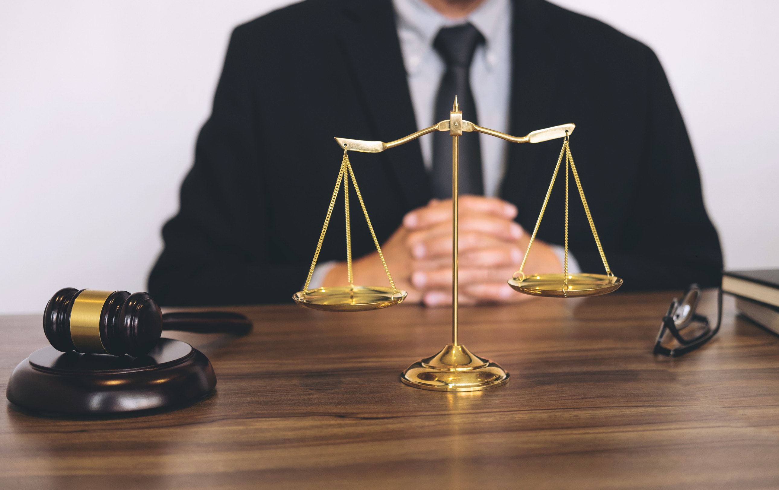 A personal injury solicitor wearing a suit sits behind a pair of golden scales