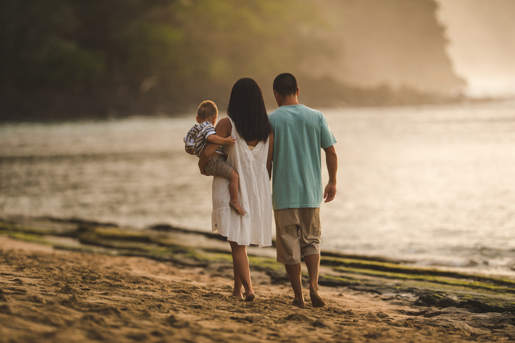 Family of three walking on a beach in Hawaii. 